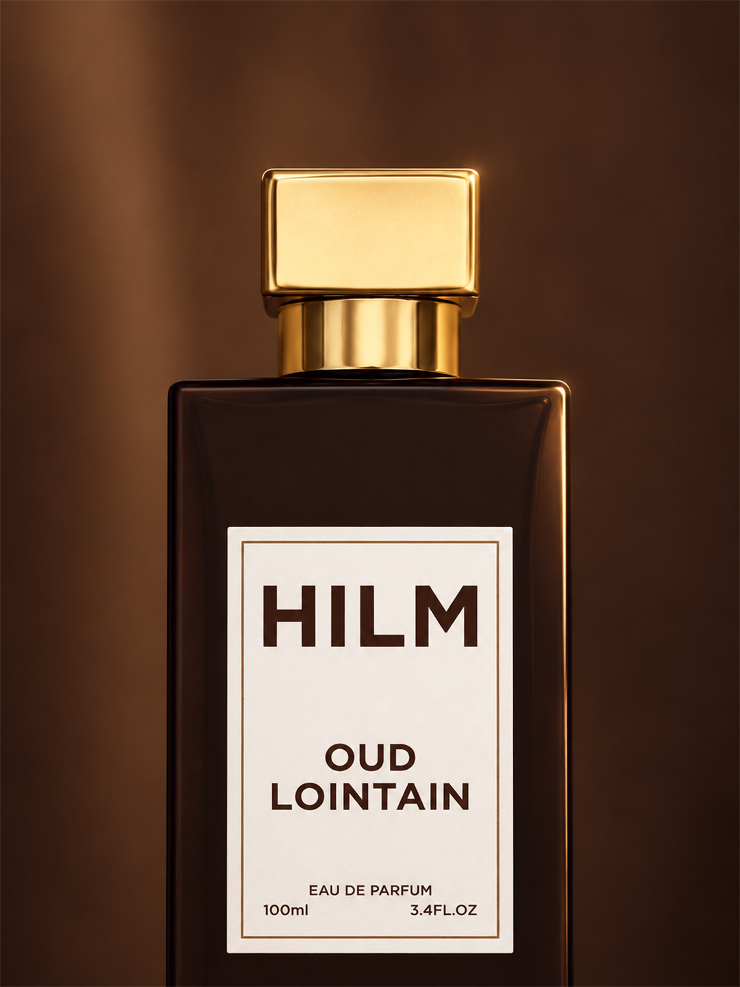 A bottle of Hilm Oud Lointain Eau de Parfum, 100ml, featuring a dark brown rectangular glass bottle with a shiny gold cap and a cream-colored label.